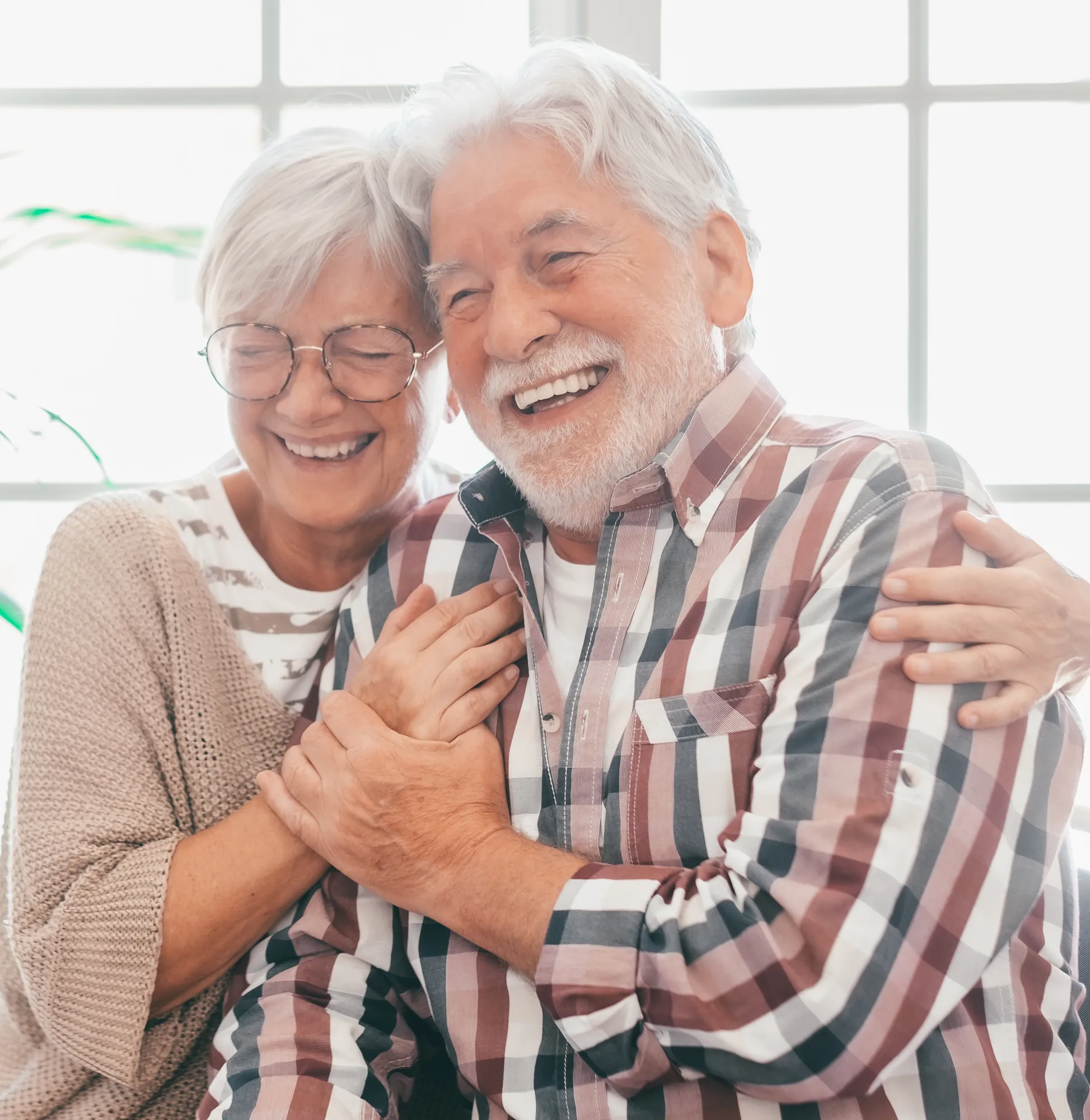 Happy senior couple laughing and embracing at home