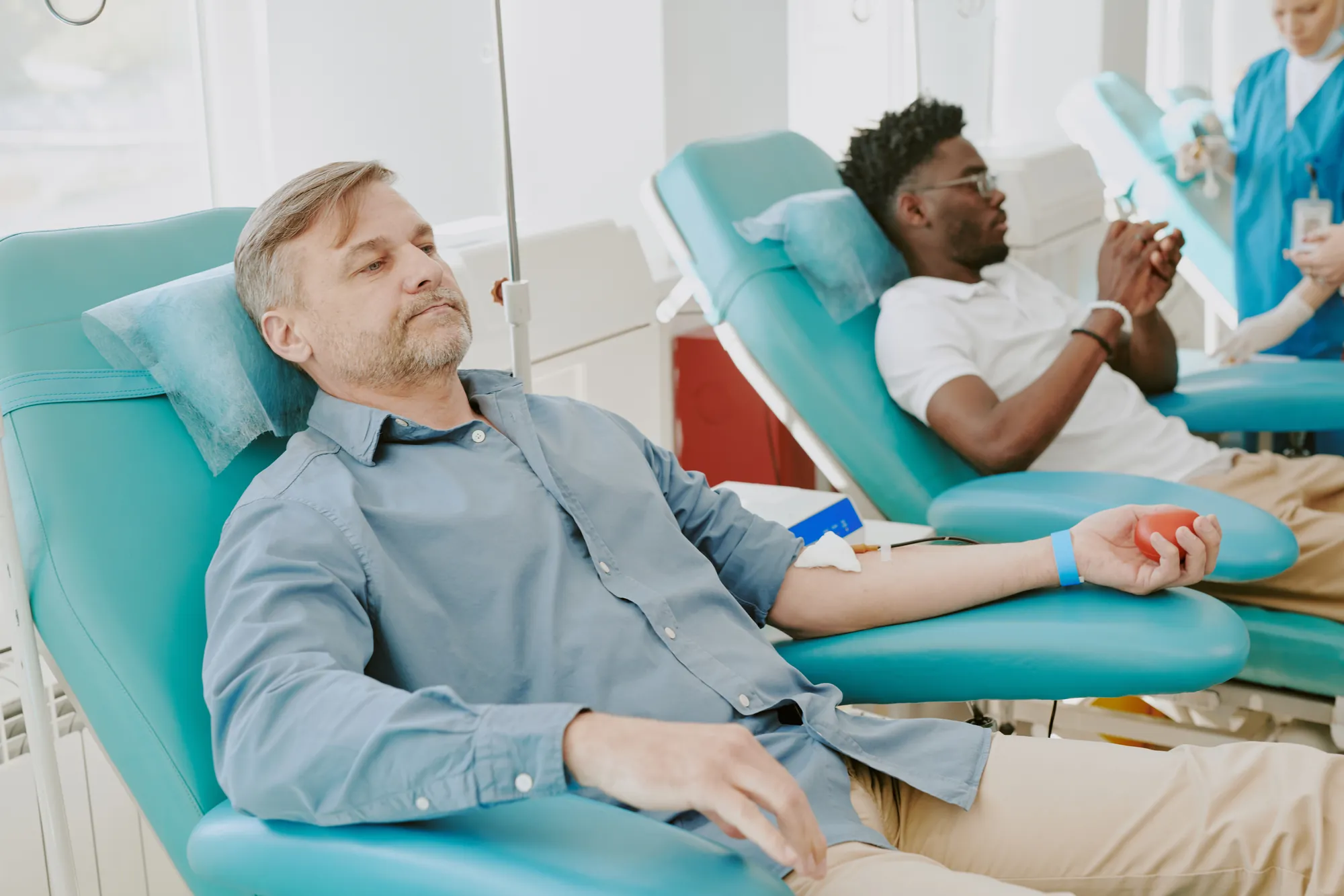 Patients resting in teal treatment chairs in a bright clinic