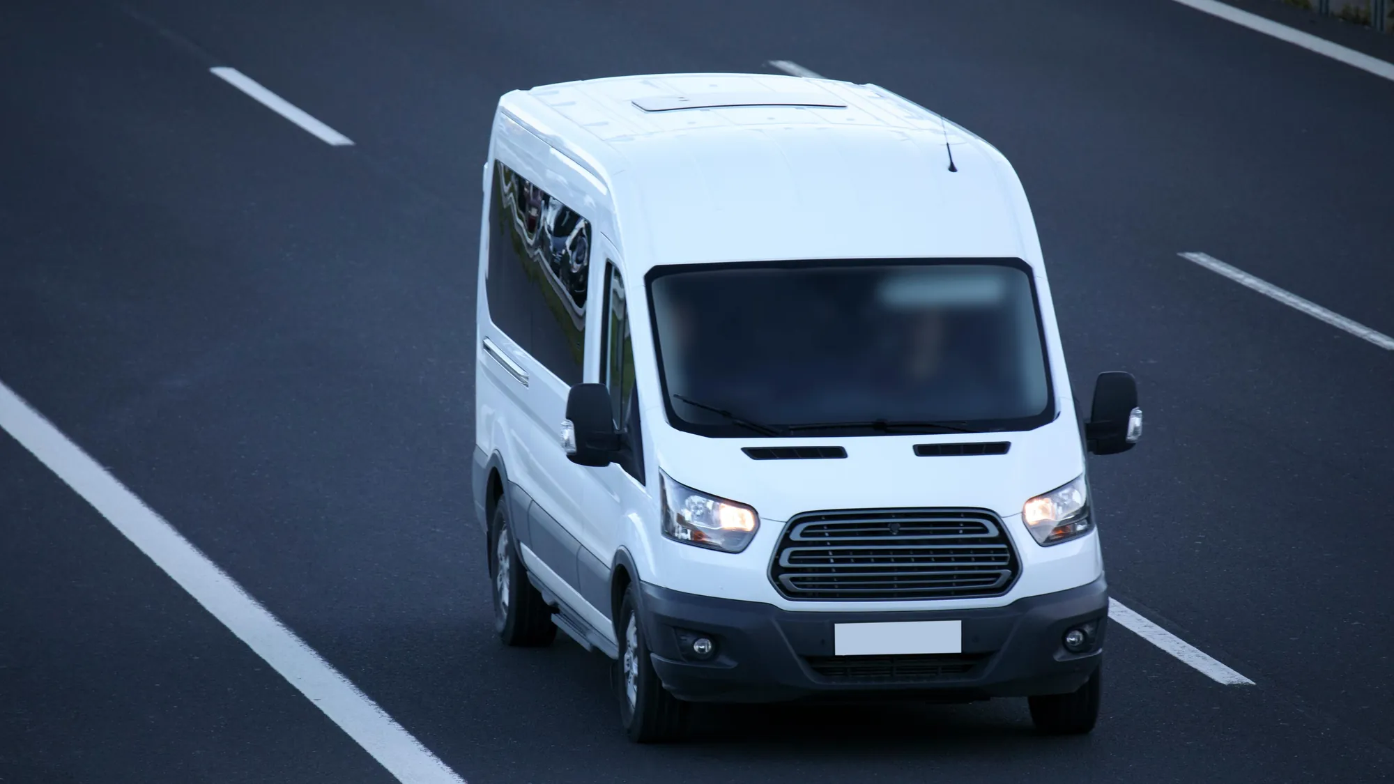 White passenger van driving on a multi-lane highway