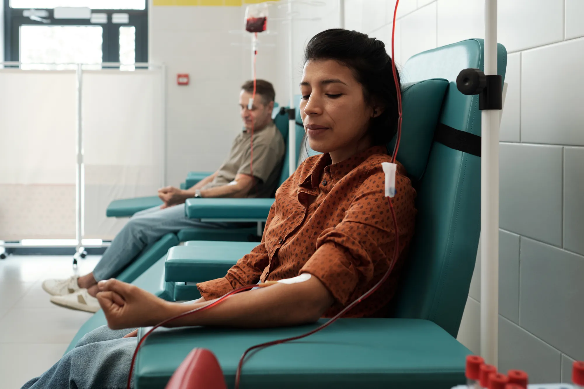 Woman resting with eyes closed in a teal treatment chair at a clinic